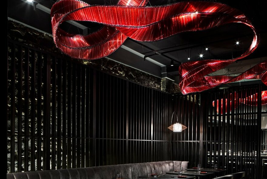 Underground bar with red lighting feature snaking across the ceiling.