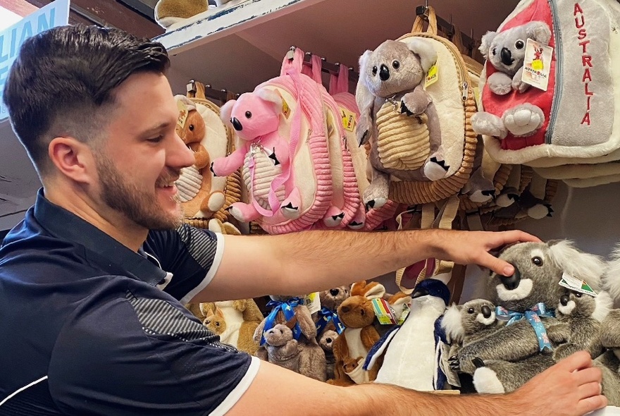 Store assistant adjusting displays of Australian animal toys and bags.