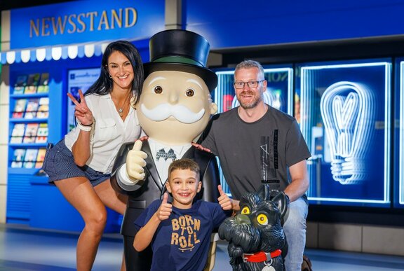 A smiling family of three posed with Mr Monopoly at Monopoly Dreams.
