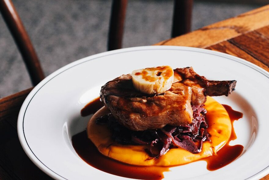 A steak on a bed of polenta with a red wine jus.