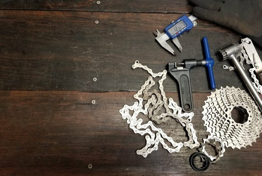 Bike chains and tools on a wooden floor.