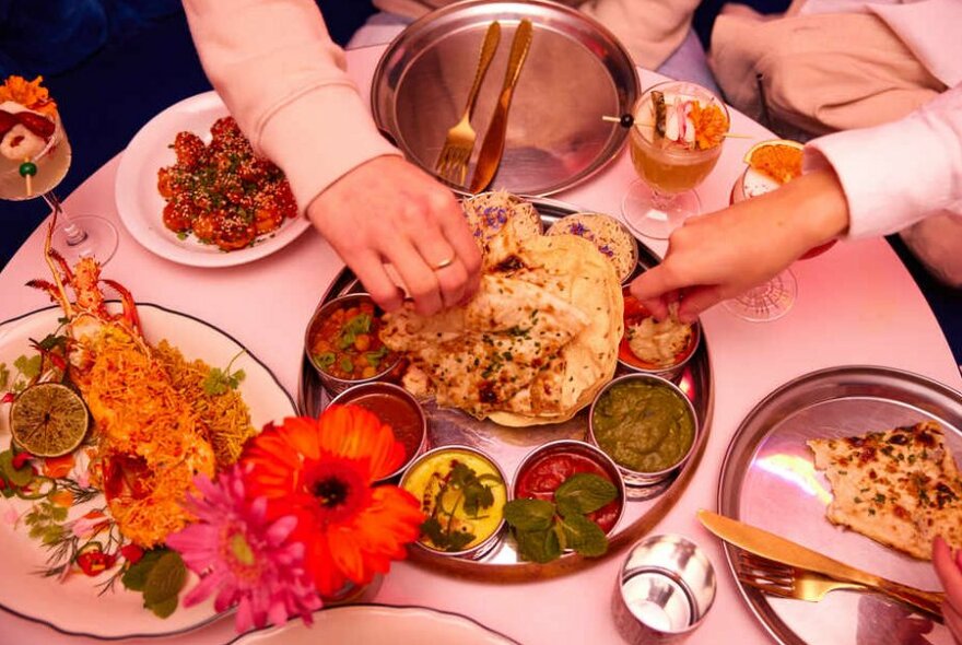 People's hands reaching for food at an Indian restaurant