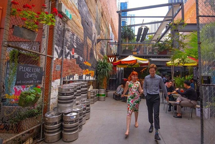 Two people strolling out of a laneway bar.