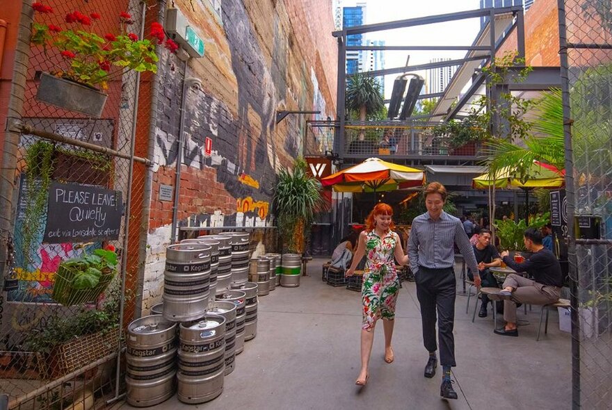 Two people strolling out of a laneway bar.