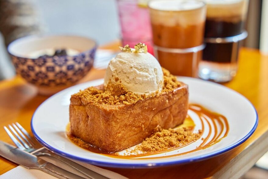 A thick slice of bread with vanilla ice cream, biscoff crumbs and caramel sauce on top