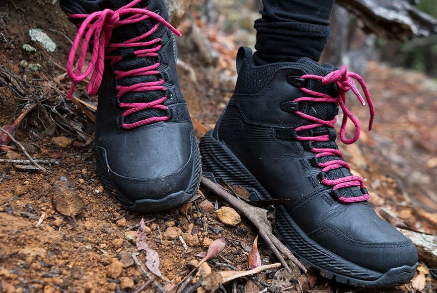 Pair of black boots with pink laces.