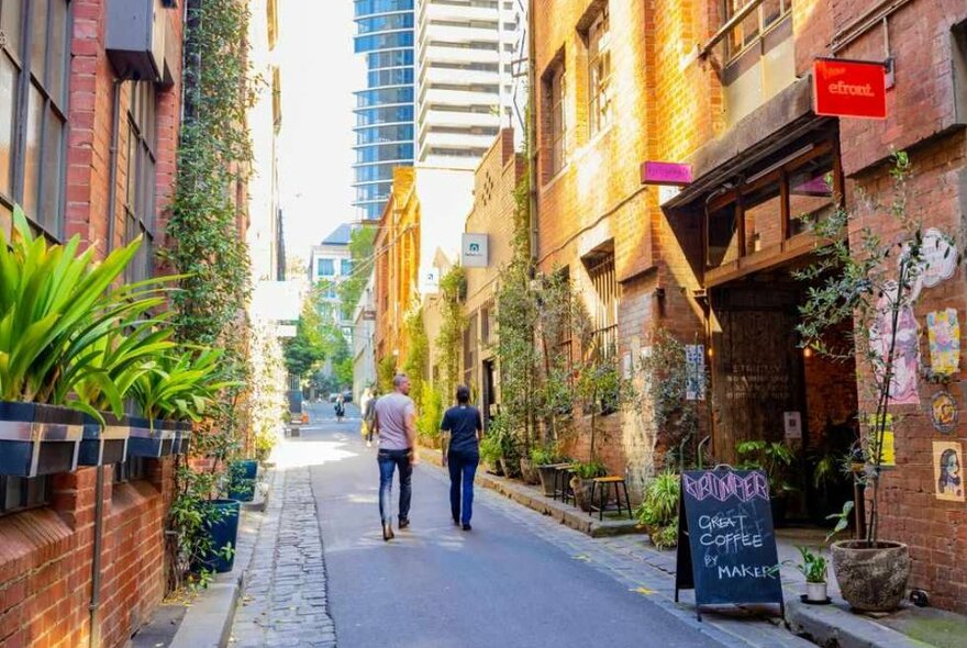 A couple walking down a laneway past brick buildings