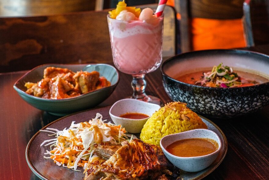 A group of dishes on a table and a pink fruit drink