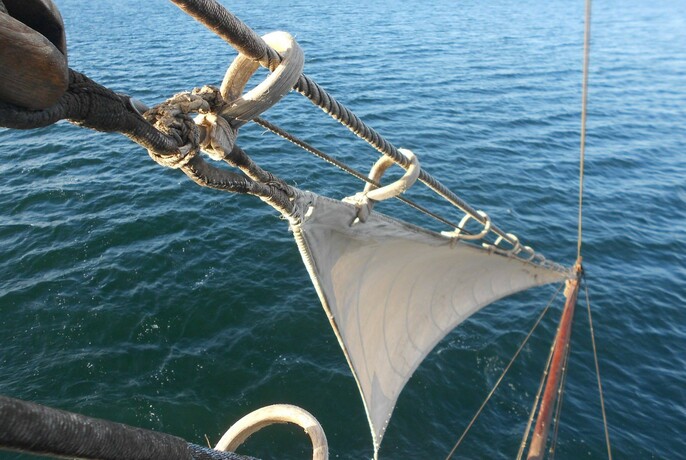 Small headsail on a schooner sailing across a blue sea. 