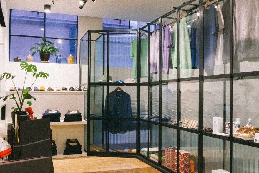 A shop corner with black and glass display cases, containing clothing jeans and shoes.