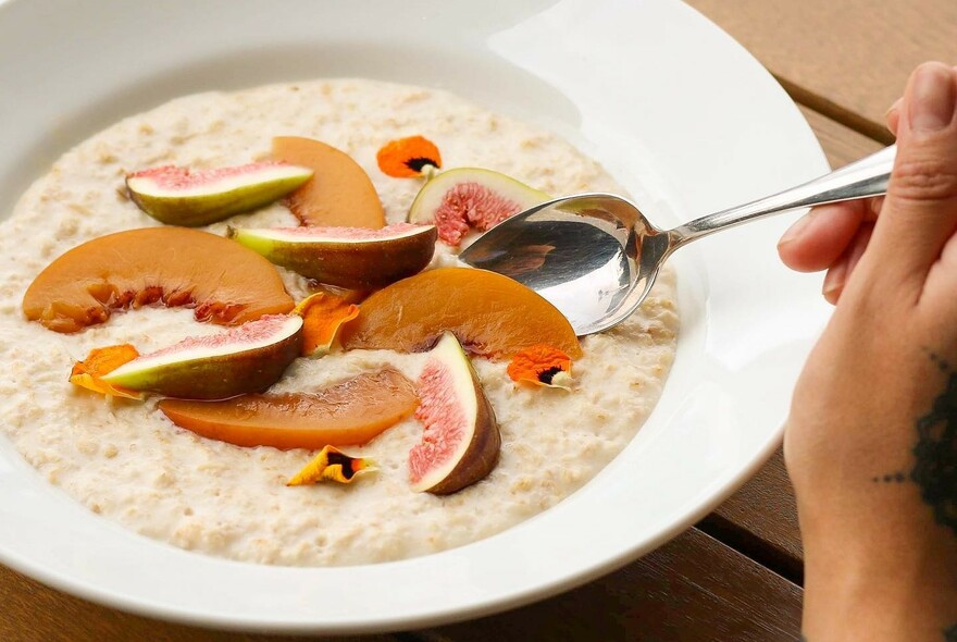 Bowl of porridge topped with fruits.