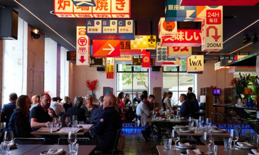 Wide shot of groups of people dining under unique Japanese signs.