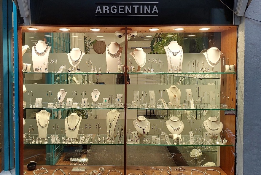 Jeweller's shopfront with signage and glass cabinets stocked with necklace stands and items for sale.