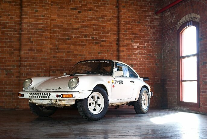 A sporty vintage Porsche with custom details parked next to a redbrick wall.