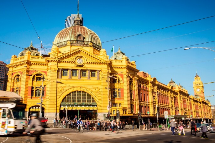 Red and yellow brick historic Flinders Street Railway Station with a dome and series of clocks.