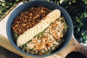 Healthful breakfast bowl with row of chopped banana, toasted coconut and toasted nuts.