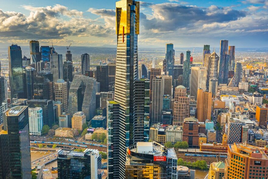 Gold-plated Eureka Tower skyscraper and cityscape against the city skyline and blue sky with clouds.