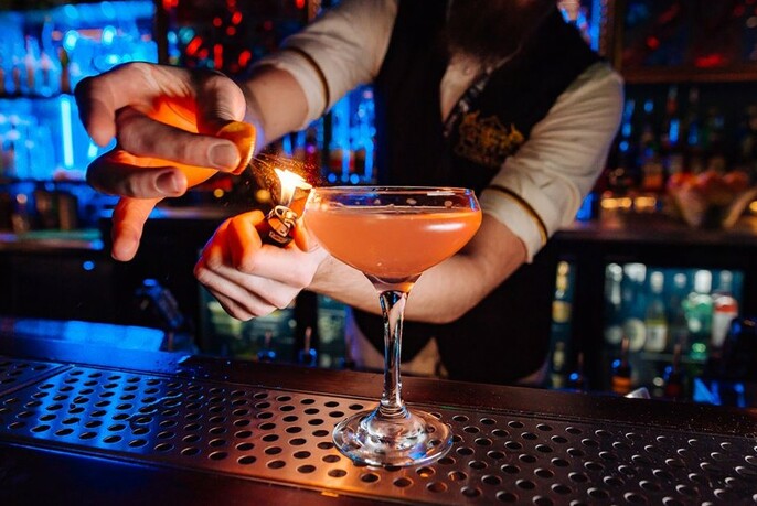 Bartender lighting a garnish on a cocktail.