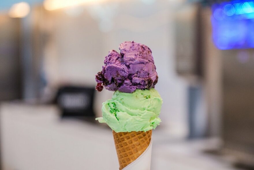 Waffle ice cream cone with green and purple scooped ice cream.