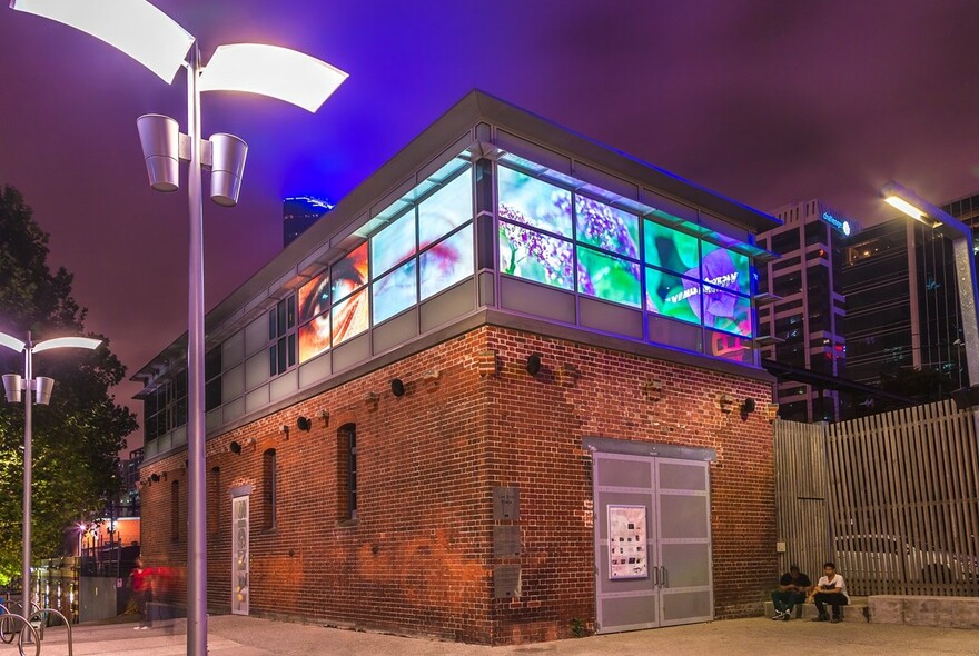 Small brick building illuminated at night, housing Signal creative arts studio.