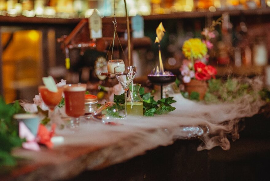 Bar counter with a quirky line-up of drinks, ornaments and smoke.