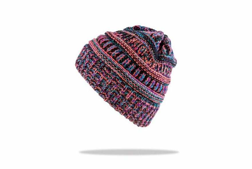 Side shot of knitted colourful beanie, colours featured are pink, orange, green, blue and black. White background with a shadow below the beanie as though it's hovering.