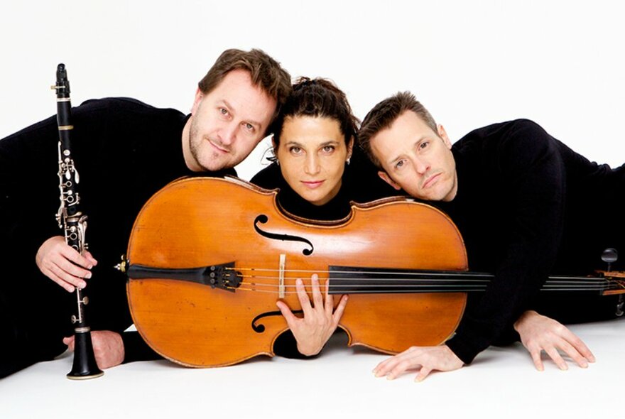 Classical ensemble lying on the floor holding a cello and clarinet.