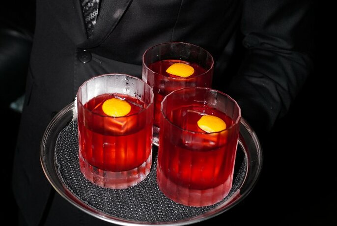Glasses of red liquor on a silver tray.
