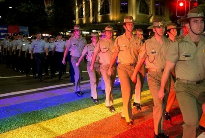 An image of Australian soldiers walking across a rainbow flag.
