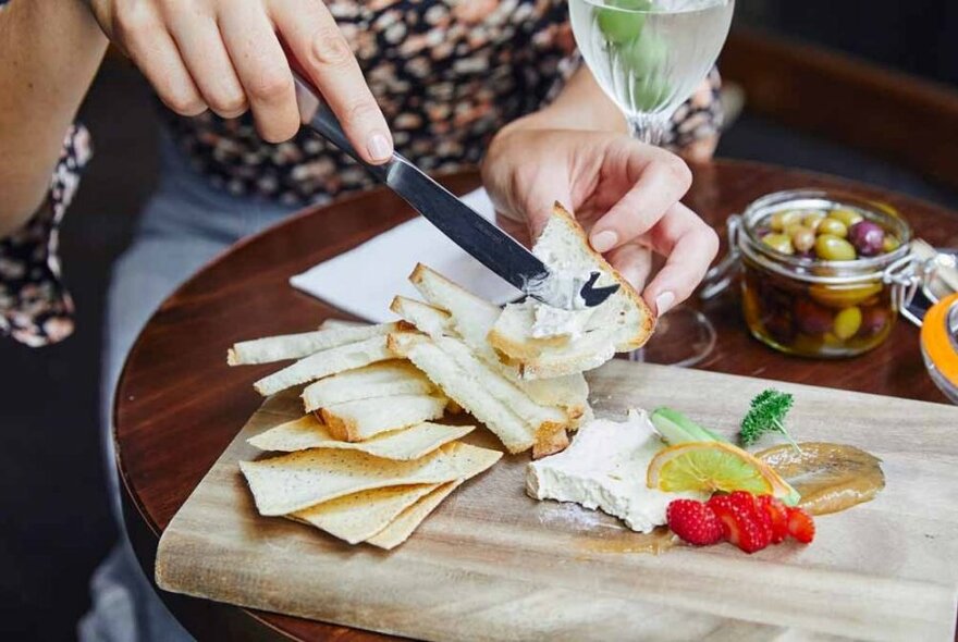 Person serving themselves from cheese platter.