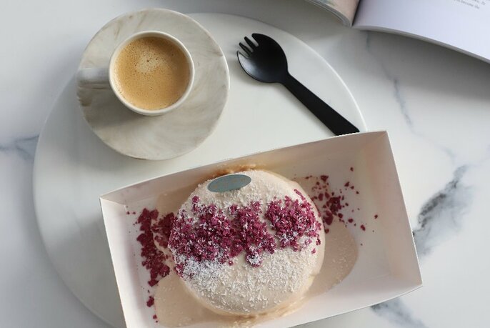 A coffee and a soufflé dessert with a berry dusting  