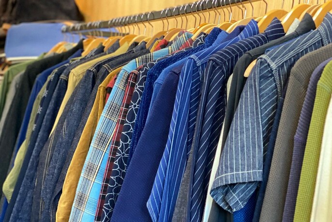 Men's long and short-sleeved shirts hanging on a rack.