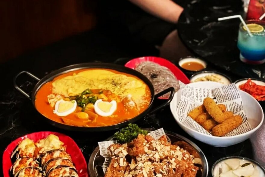 An arrangement of large plates and bowls filled with cooked Korean food.
