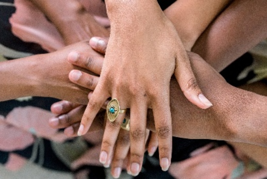 Looking down at a group of different hands, all piled on top of each other, making a hand stack.
