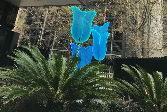 An illuminated garden installation featuring tall blue flowers.