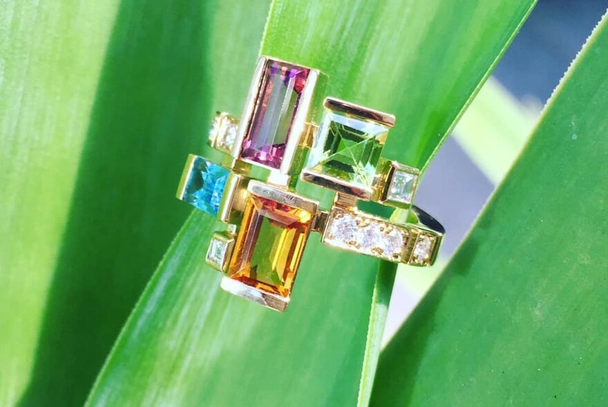 Green foliage holding contemporary-styled rings with square cut stones and diamonds.