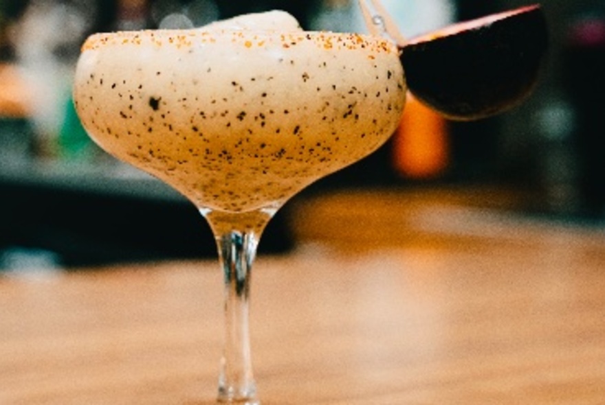 A cocktail glass filled with creamy liquid with black and brown dots.