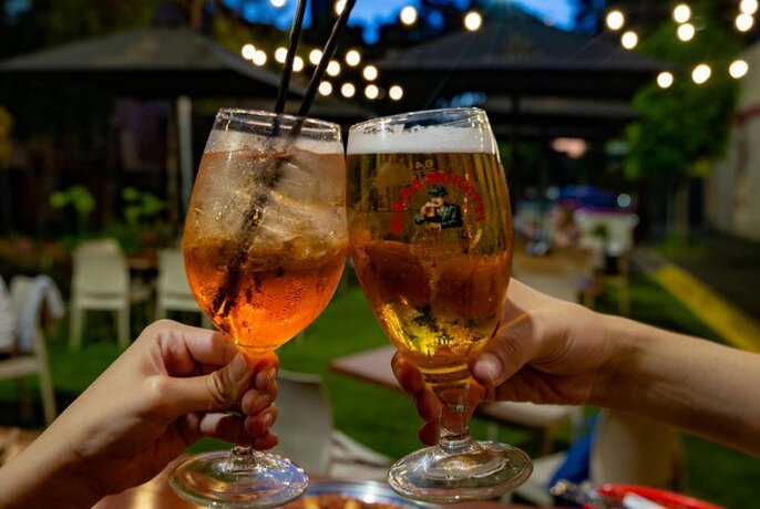 Two glasses of alcohol being held outside in the evening.