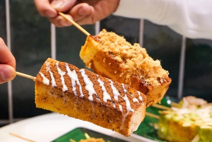 Two fried desserts on skewers.