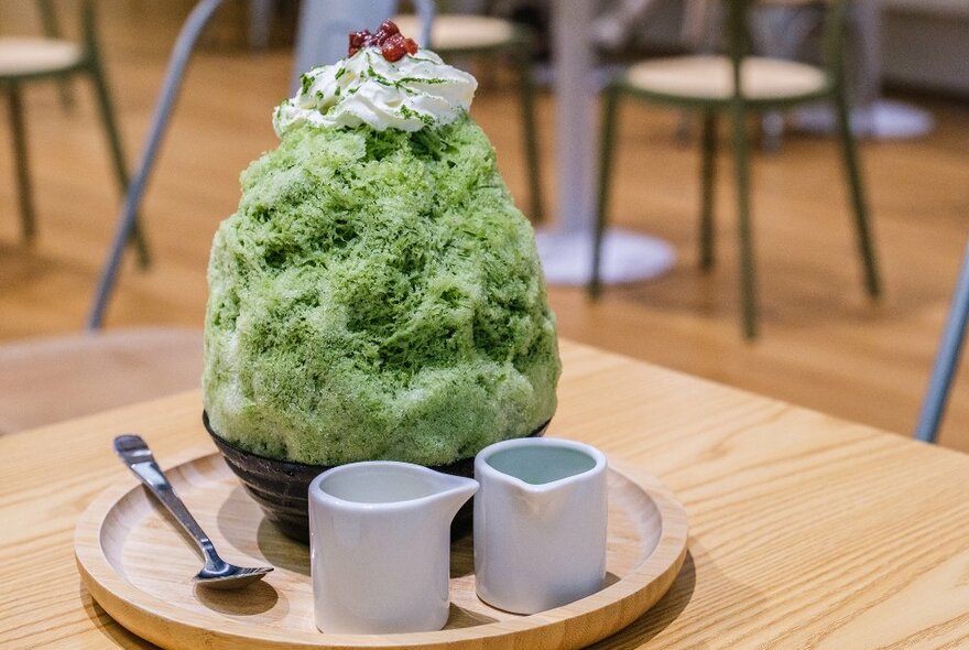 A matcha shaved iced dessert with cream on top