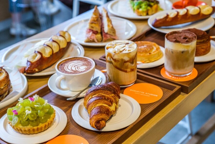 A cafe table set with coffees, pastries and desserts.