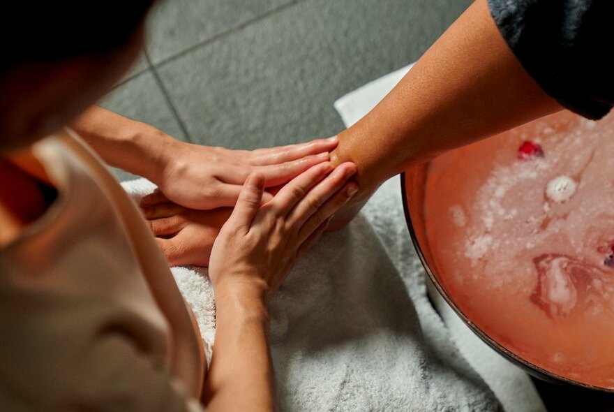 A therapist massaging a customer's foot, resting white towels.