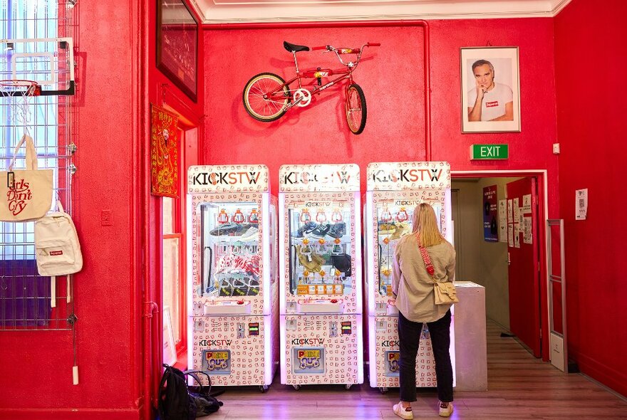 A woman is playing with a vending machine in a streetwear shop.