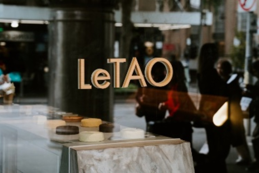 Looking through a shop window with the signage LeTAO, with products on display on a counter.