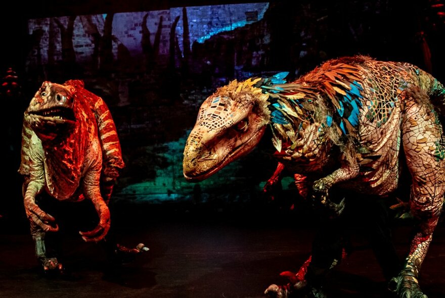 Large dinosaur theatrical puppets on a stage.