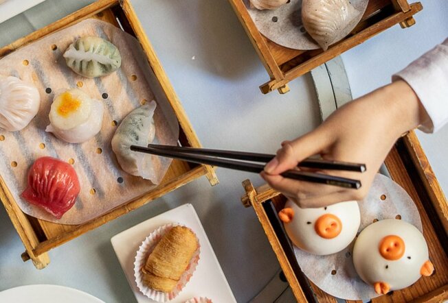 A selection of dumplings include pig shaped buns being eaten with chopsticks.