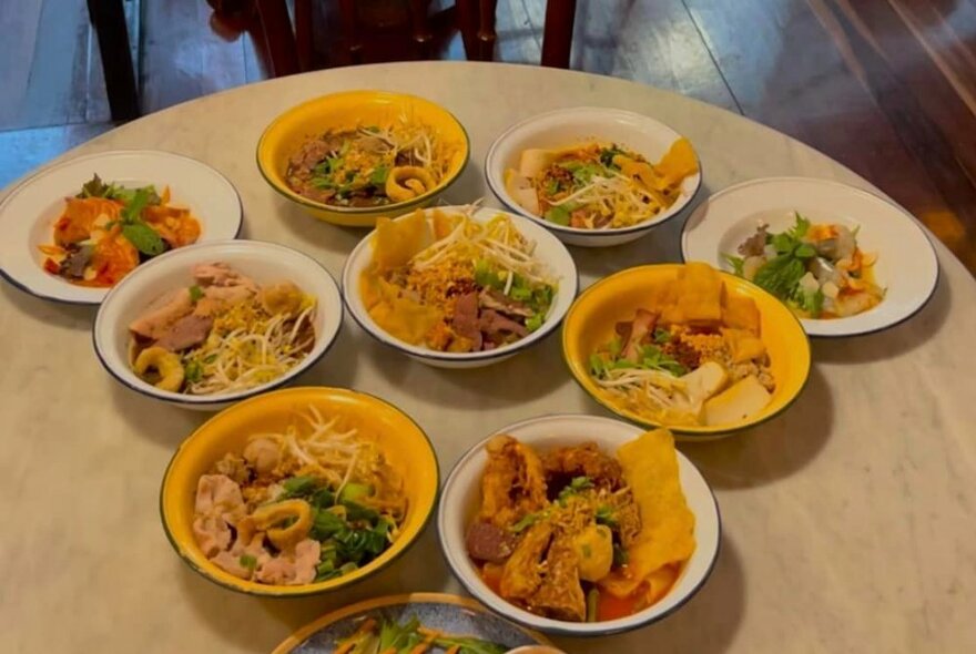 Several bowls of Thai food displayed on a table in a restaurant.
