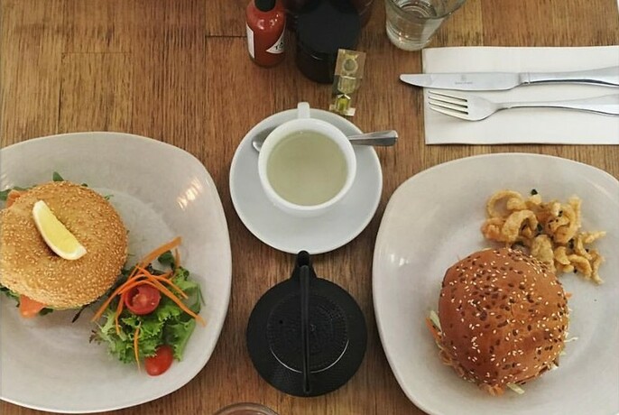 Plates containing a salad bagel and a hamburger.