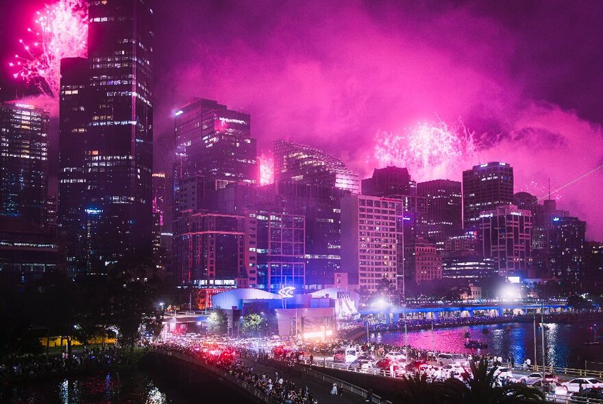 Melbourne city skyline looking pink with exploding fireworks.