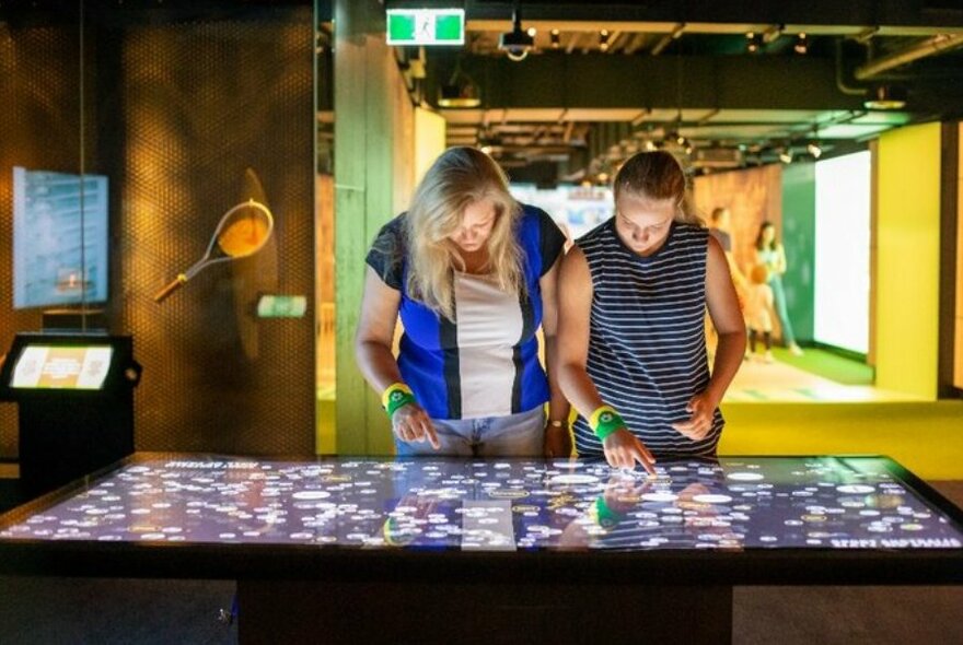 Two people looking at and touching an interactive touch screen.